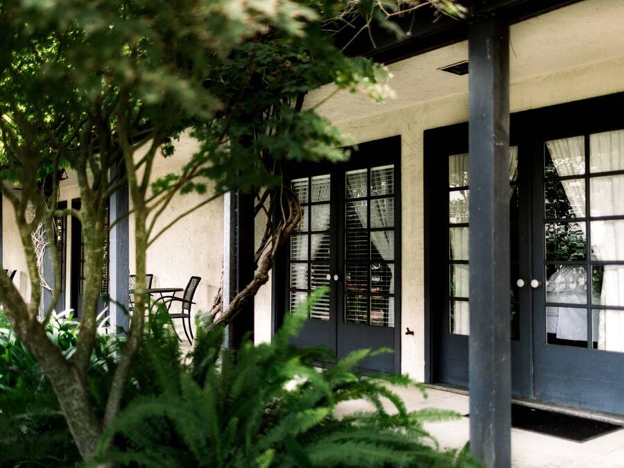A building with a covered porch, black-framed windows, and a door with a doormat.
