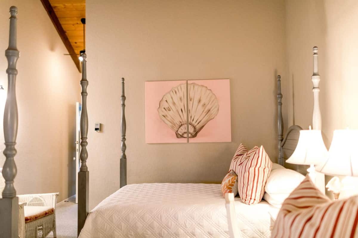 A bedroom with a bed, a nightstand, a lamp, a wall-mounted artwork, and a crib.