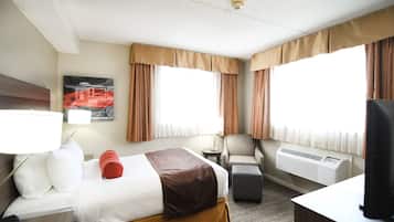 A hotel room with a bed, a chair, a desk, a lamp, and a television.