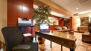 A hotel lobby with a desk, computer, leather chairs, a large plant, and a reception desk. - Best Western Plus Sandusky Hotel & Suites (Sandusky)