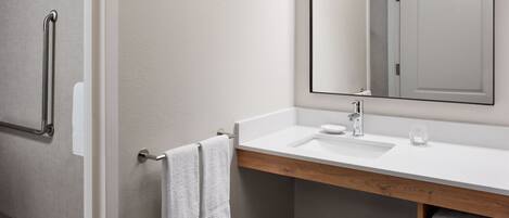 A modern bathroom with a white sink, a mirror, and a towel rack.