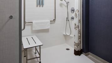 A modern bathroom with a shower, a small table, and a towel rack.