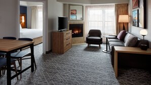Habitación de hotel con cama, televisor, chimenea, sofá, mesita de centro y escritorio con sillas.