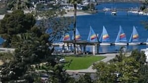 Un port de plaisance avec des voiliers et une chaîne de montagnes en arrière-plan.