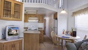 Une cuisine compacte dotée de meubles en bois, d’un îlot central et d’un coin repas avec une table et des chaises.