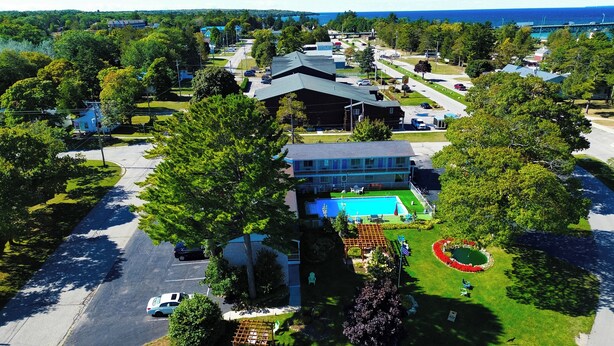 A residential area with a large house featuring a swimming pool, surrounded by trees and a well-maintained lawn. - American Boutique Inn - Lakeview (Mackinaw City)