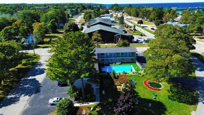 Un quartier résidentiel avec une grande maison dotée d’une piscine, entourée d’arbres et d’une pelouse bien entretenue.