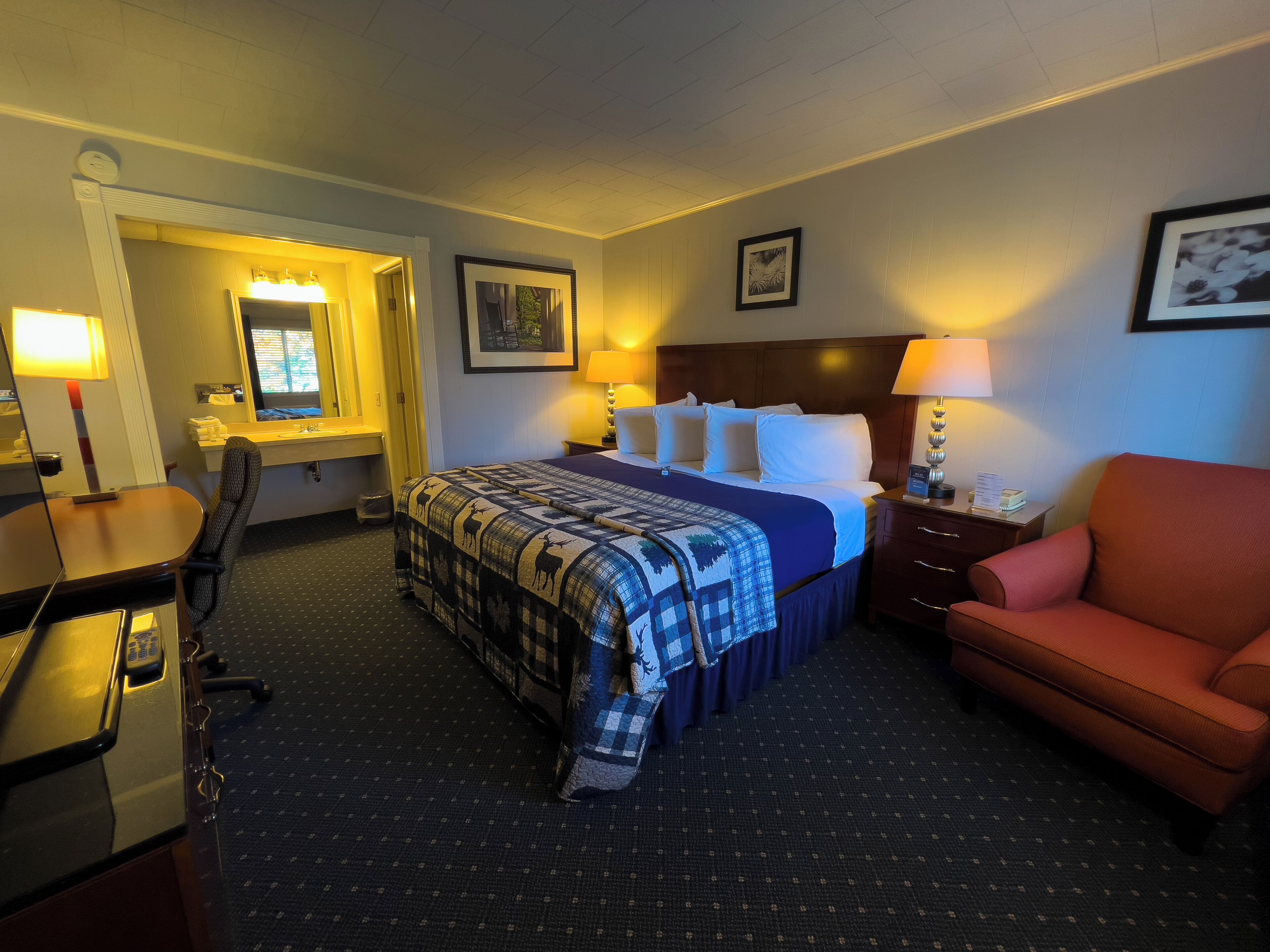 Una habitación de hotel con cama, escritorio, silla y mesita de noche.