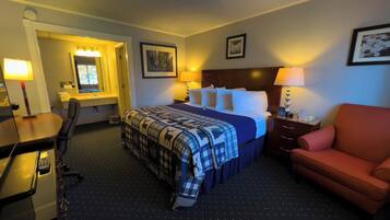 Una habitación de hotel con cama, escritorio, silla y mesita de noche.