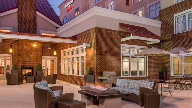 An outdoor patio area with brick walls, a fire pit, and outdoor furniture.