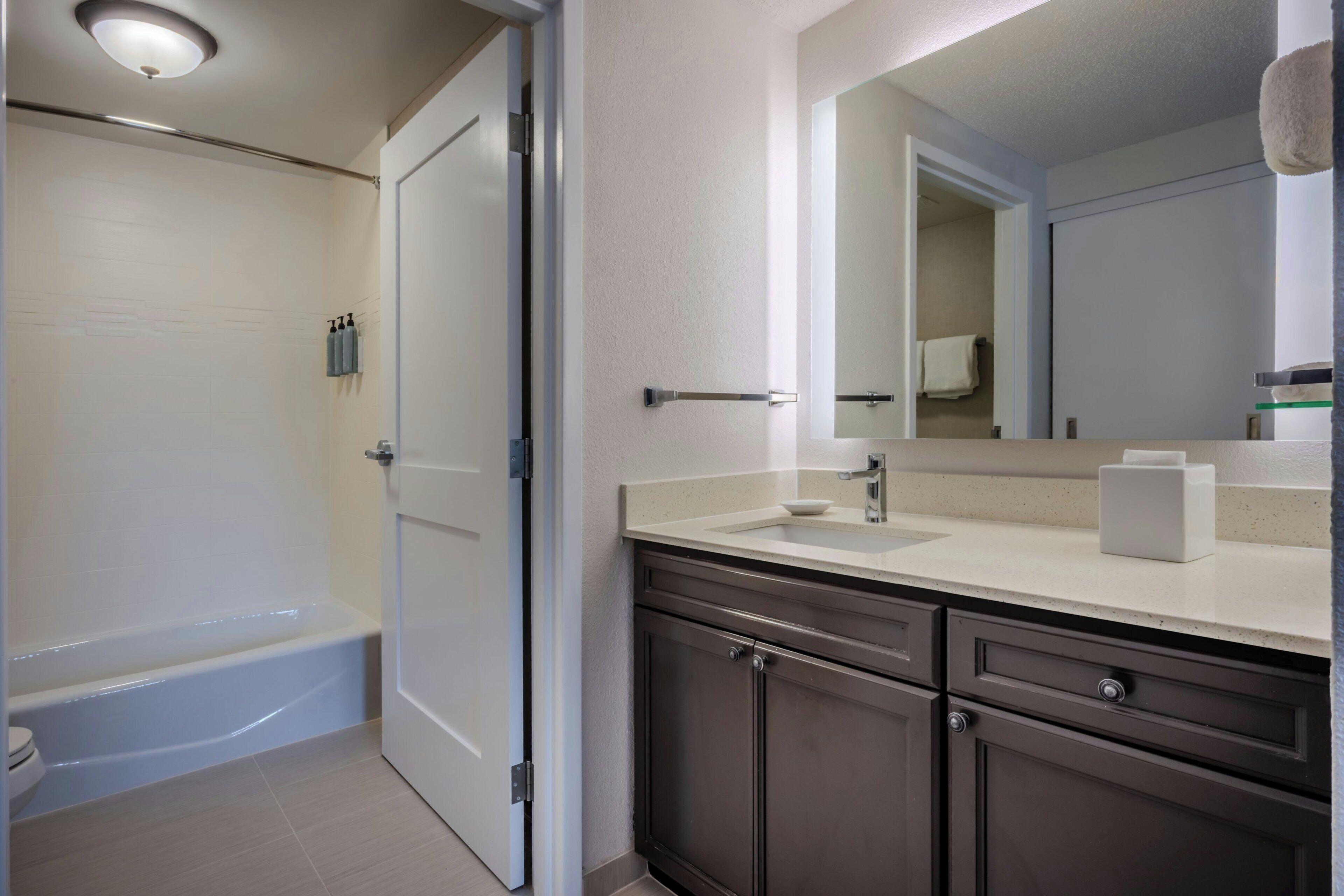 A bathroom with a bathtub, a sink with a mirror, and a toilet.