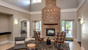 A spacious living area with a stone fireplace, comfortable seating, and large windows.