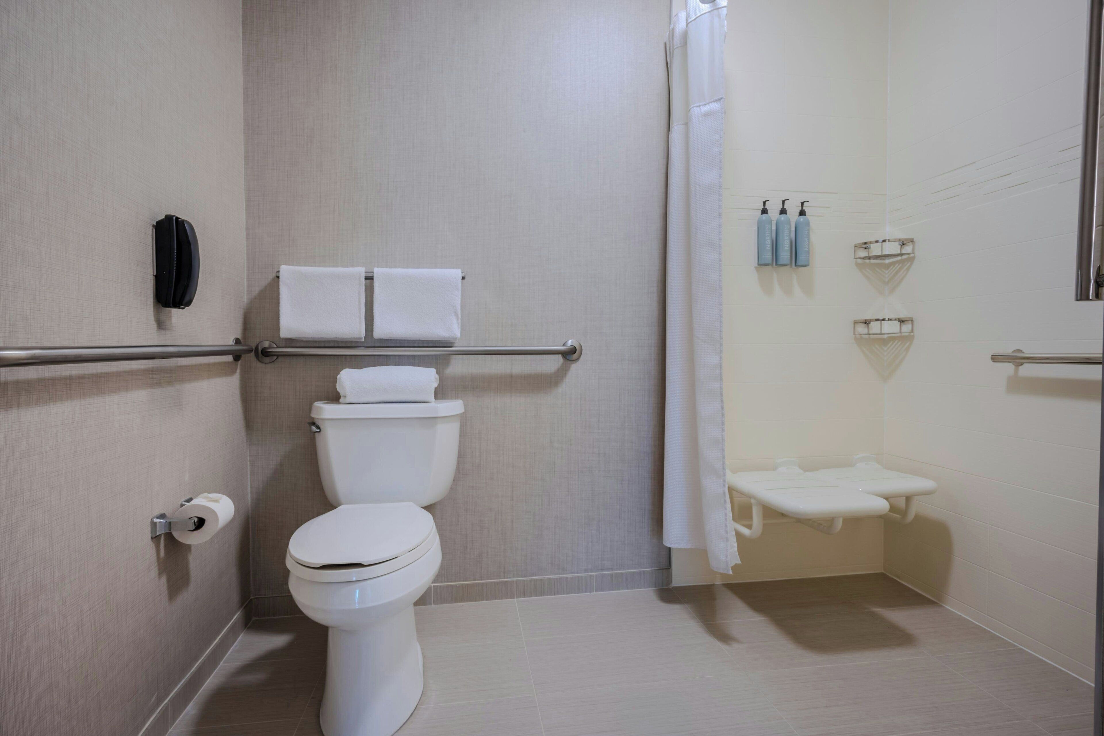 Une salle de bain moderne équipée de toilettes, d’un sèche-mains et d’un espace douche.