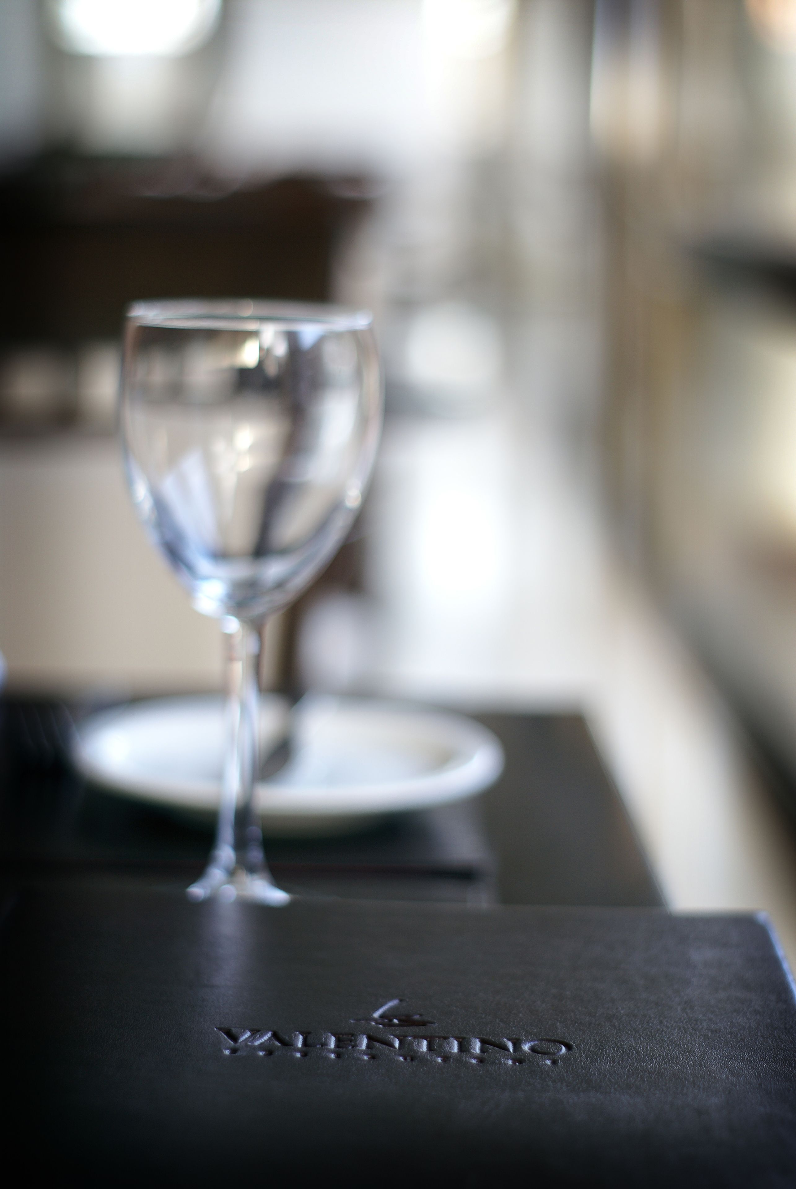 A wine glass on a black table with embossed text.