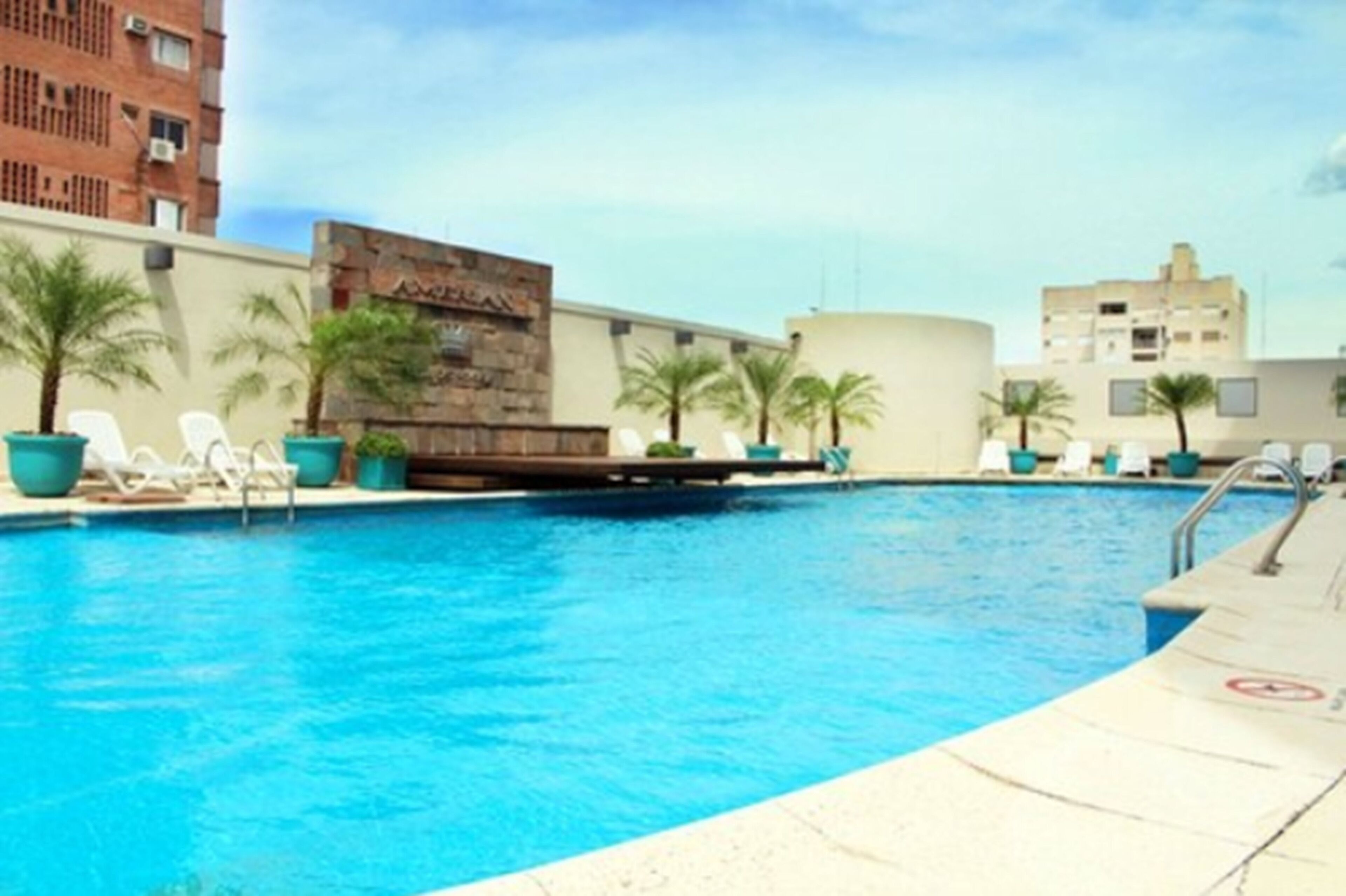 A swimming pool with lounge chairs and palm trees.