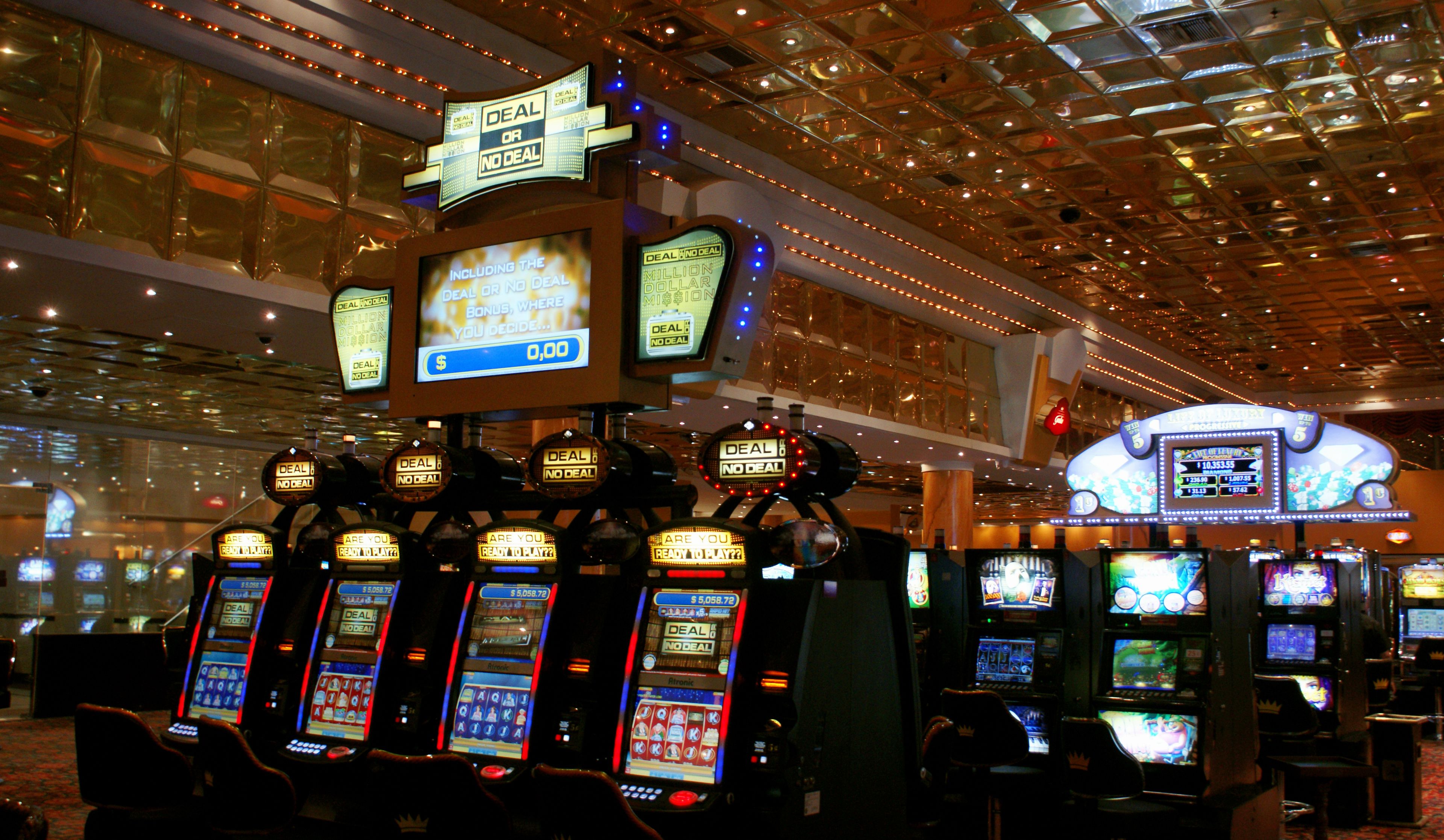 A casino with multiple slot machines and a large illuminated sign overhead.