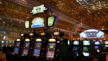 A casino with multiple slot machines and a large illuminated sign overhead.