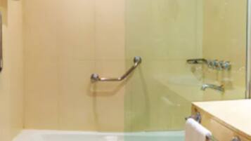 A bathroom with a glass shower enclosure, a bathtub, and a towel hanging on the wall.