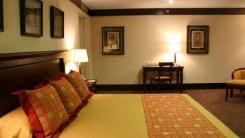 Una habitación de hotel con una cama grande, un escritorio y dos sillas.