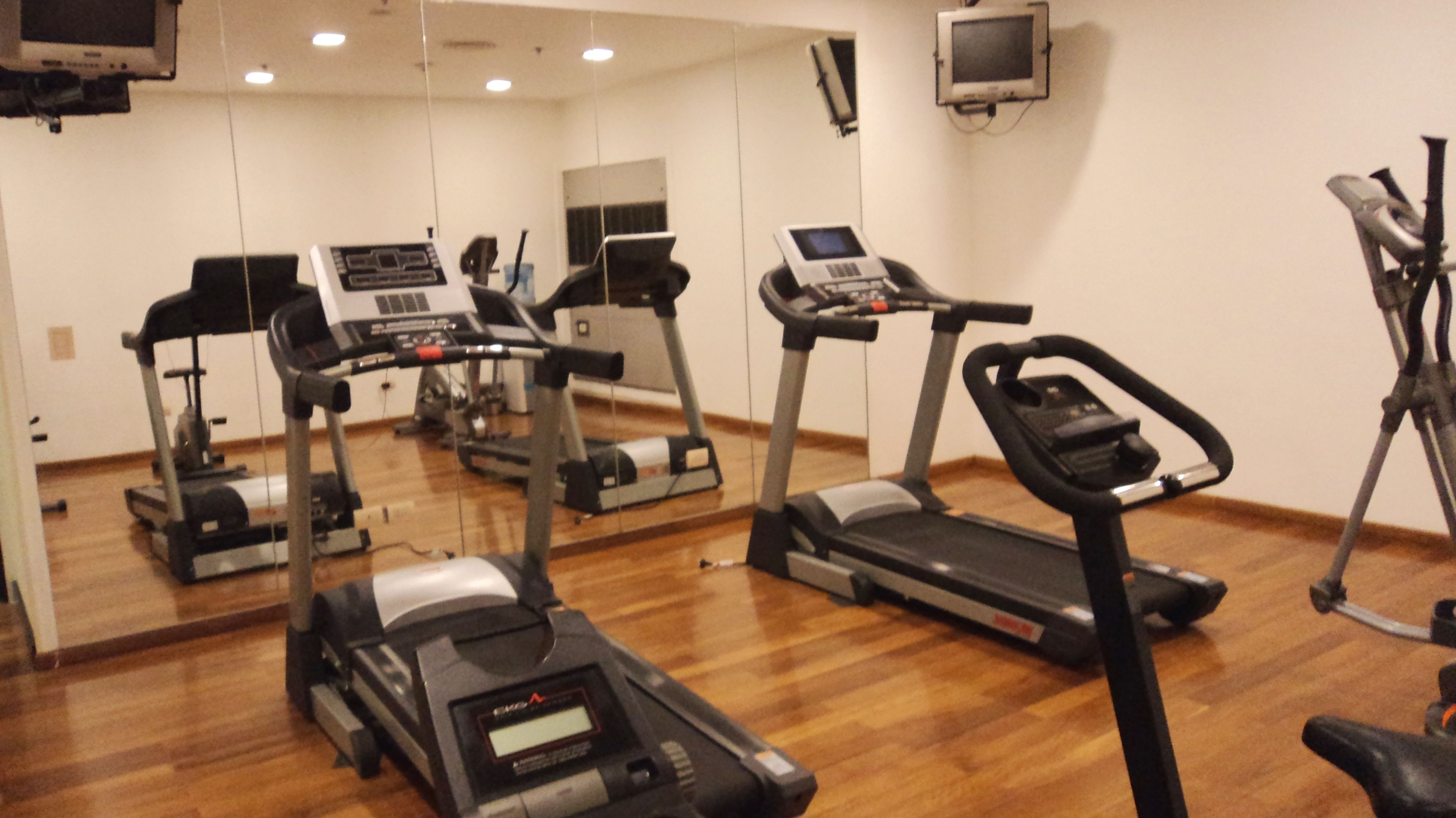 Une salle de sport équipée de tapis de course, d’appareils elliptiques et de vélos d’appartement.