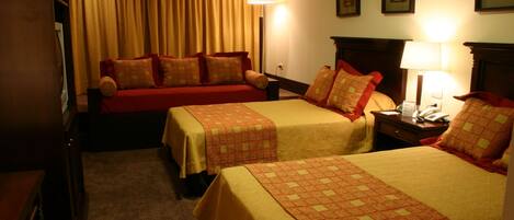 Une chambre d’hôtel avec deux lits, un bureau, une chaise, une lampe et une armoire.