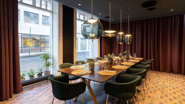 A conference room with a long table, green chairs, and modern pendant lights. - Radisson Blu 1919 Hotel, Reykjavik (Reykjavik)