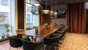 A conference room with a long table, green chairs, potted plants, and pendant lights. - Radisson Blu 1919 Hotel, Reykjavik (Reykjavik)