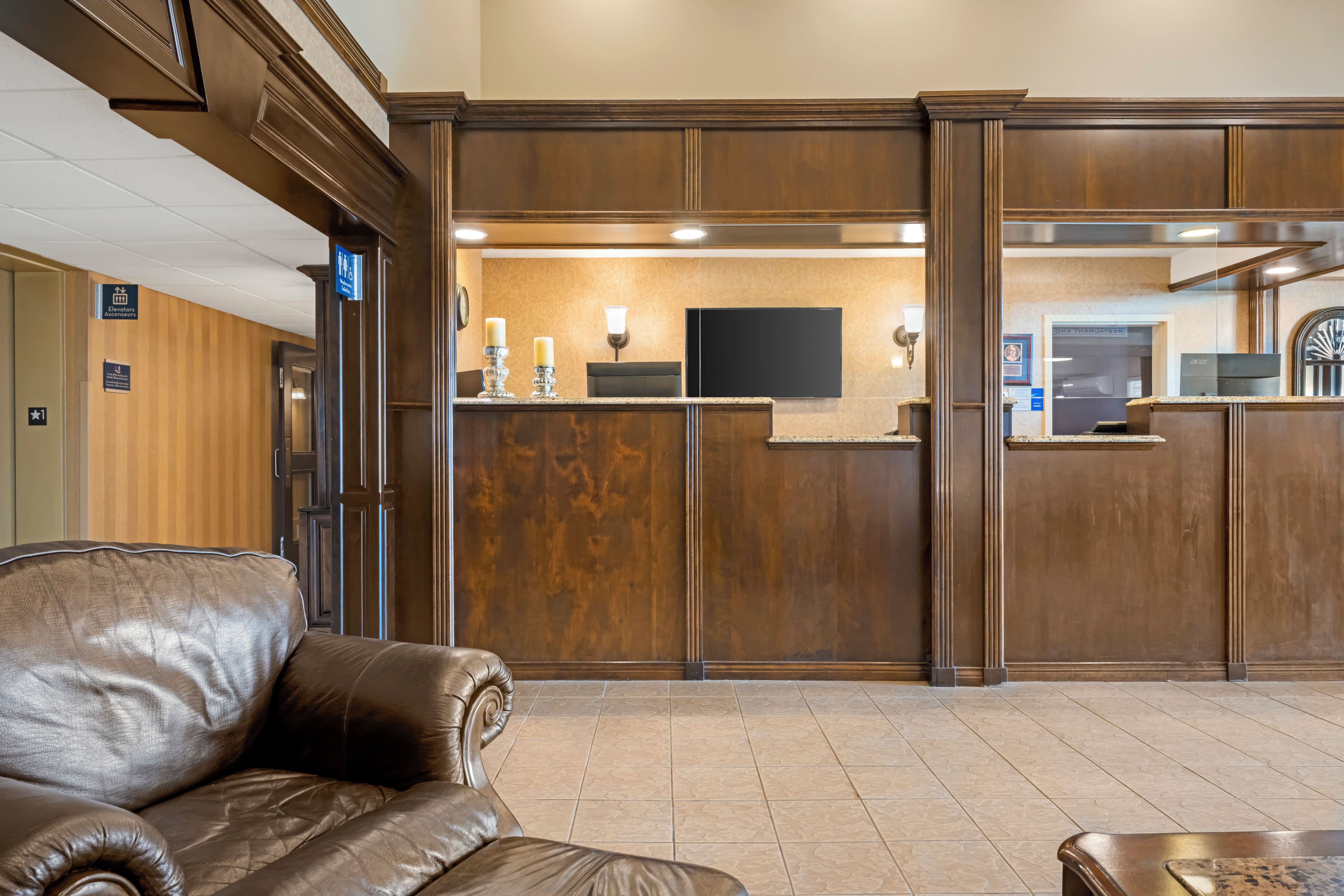 A lobby with a reception desk, a leather sofa, and a tiled floor.