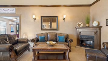 A living room with leather sofas, a coffee table, a fireplace, and wall-mounted sconces.