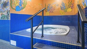 Een hottub met vloer en wanden in blauw tegels, omringd door een trap met zwarte leuningen.