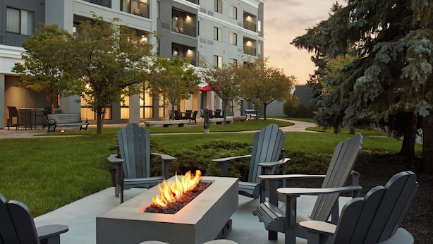 Un patio con sillas Adirondack, una chimenea y un edificio al fondo.