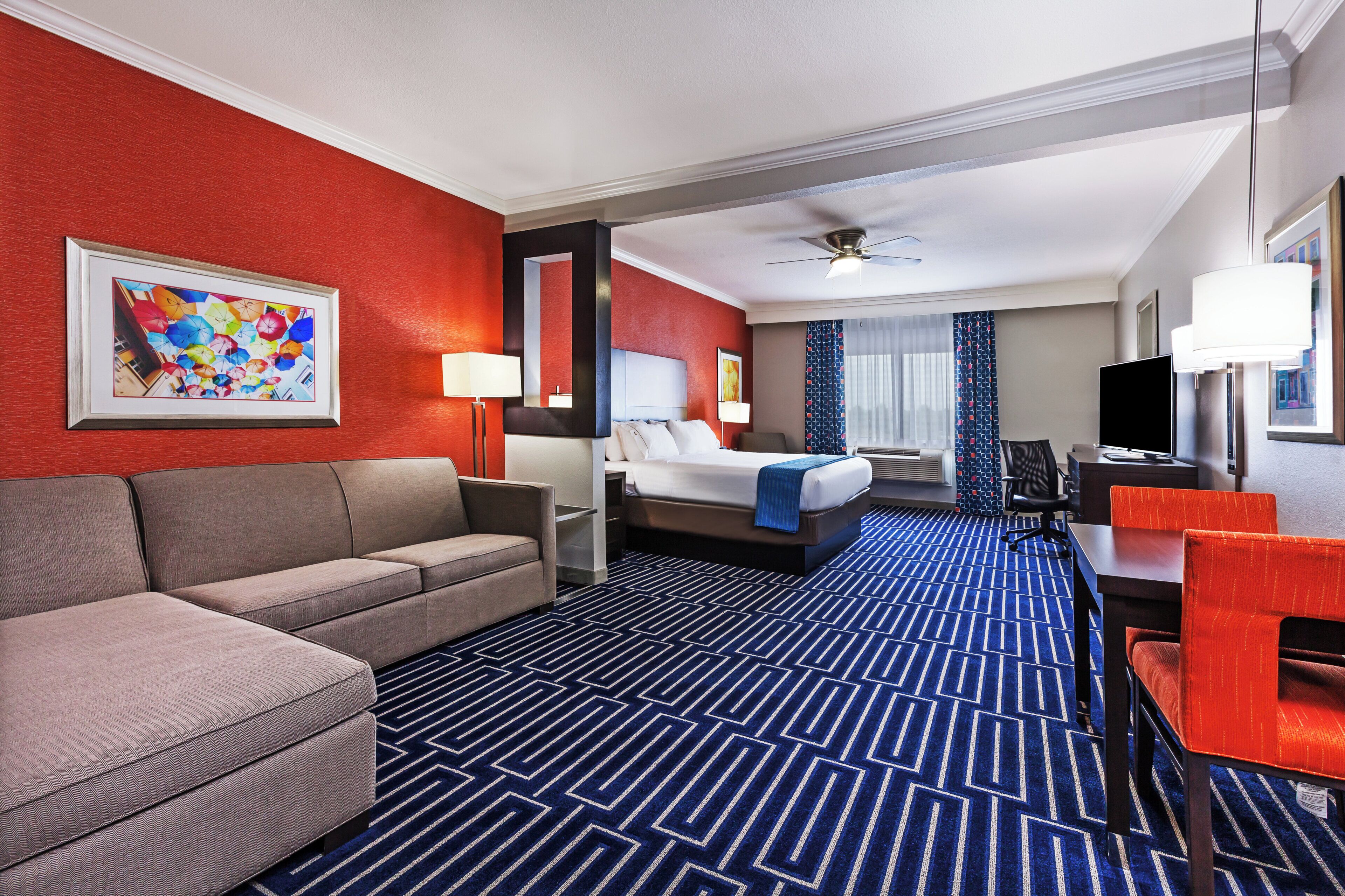 A hotel room with a sofa, a bed, a desk, and a television.