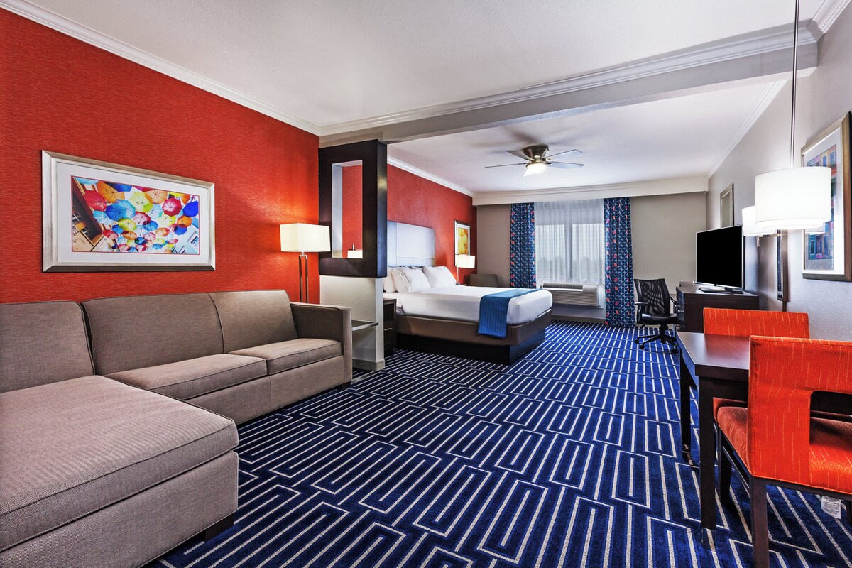 Ein Hotelzimmer mit einer Couch, einem Bett, einem Schreibtisch und einem Fernseher.