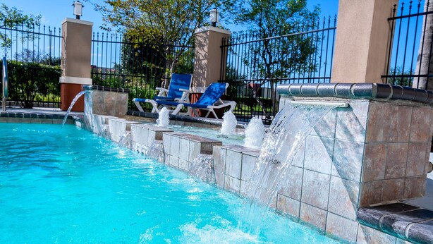 A swimming pool with water features and lounge chairs. - Holiday Inn Express & Suites Houston East, by IHG (Houston)