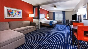 A hotel room with a large bed, a sofa, a desk, and a television. - Holiday Inn Express & Suites Houston East, by IHG (Houston)