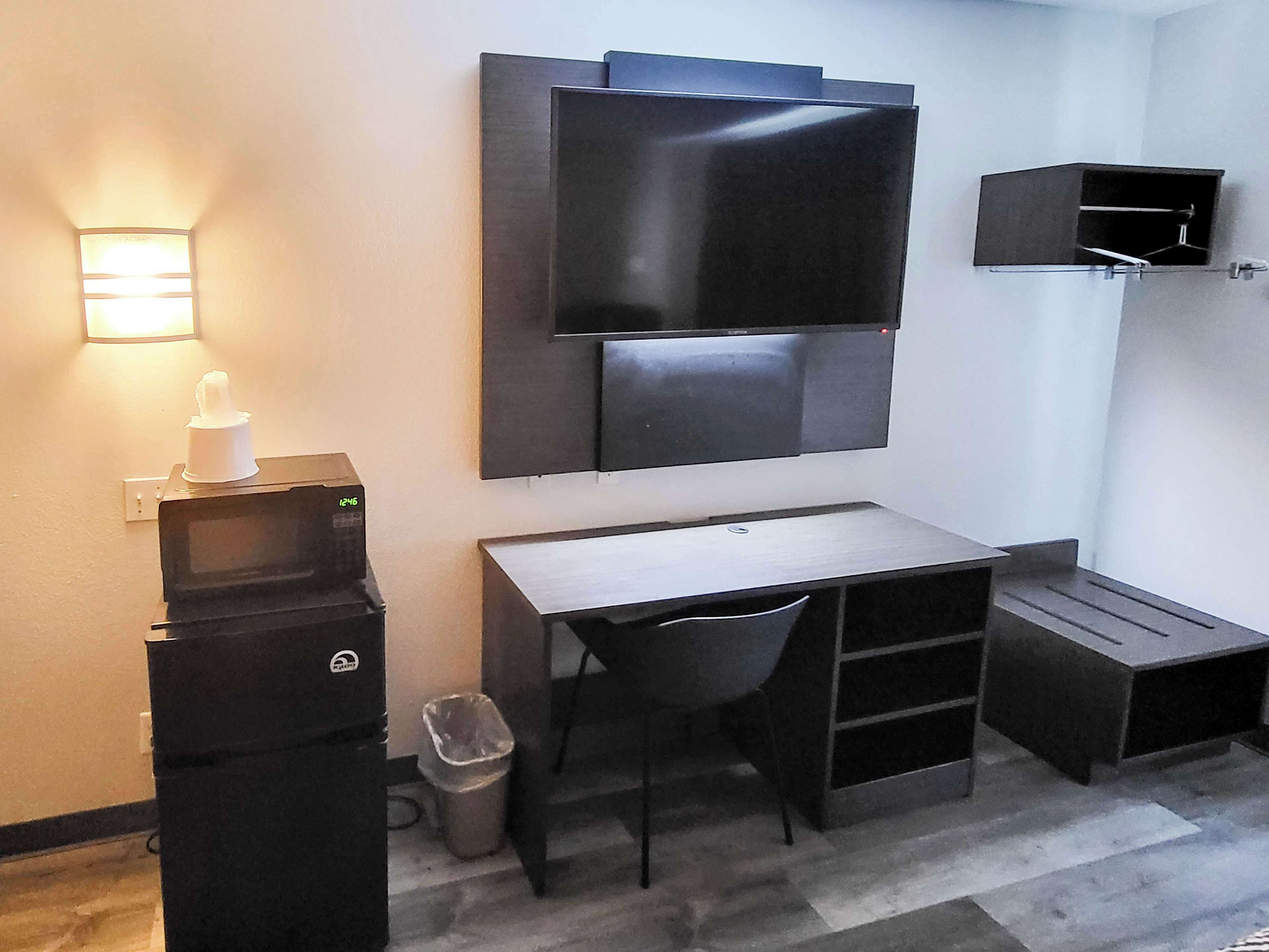 A compact room with a desk, chair, and a flat-screen TV mounted on the wall.