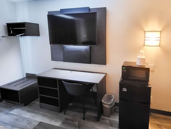 A compact room with a desk, chair, and a flat-screen TV mounted on the wall.