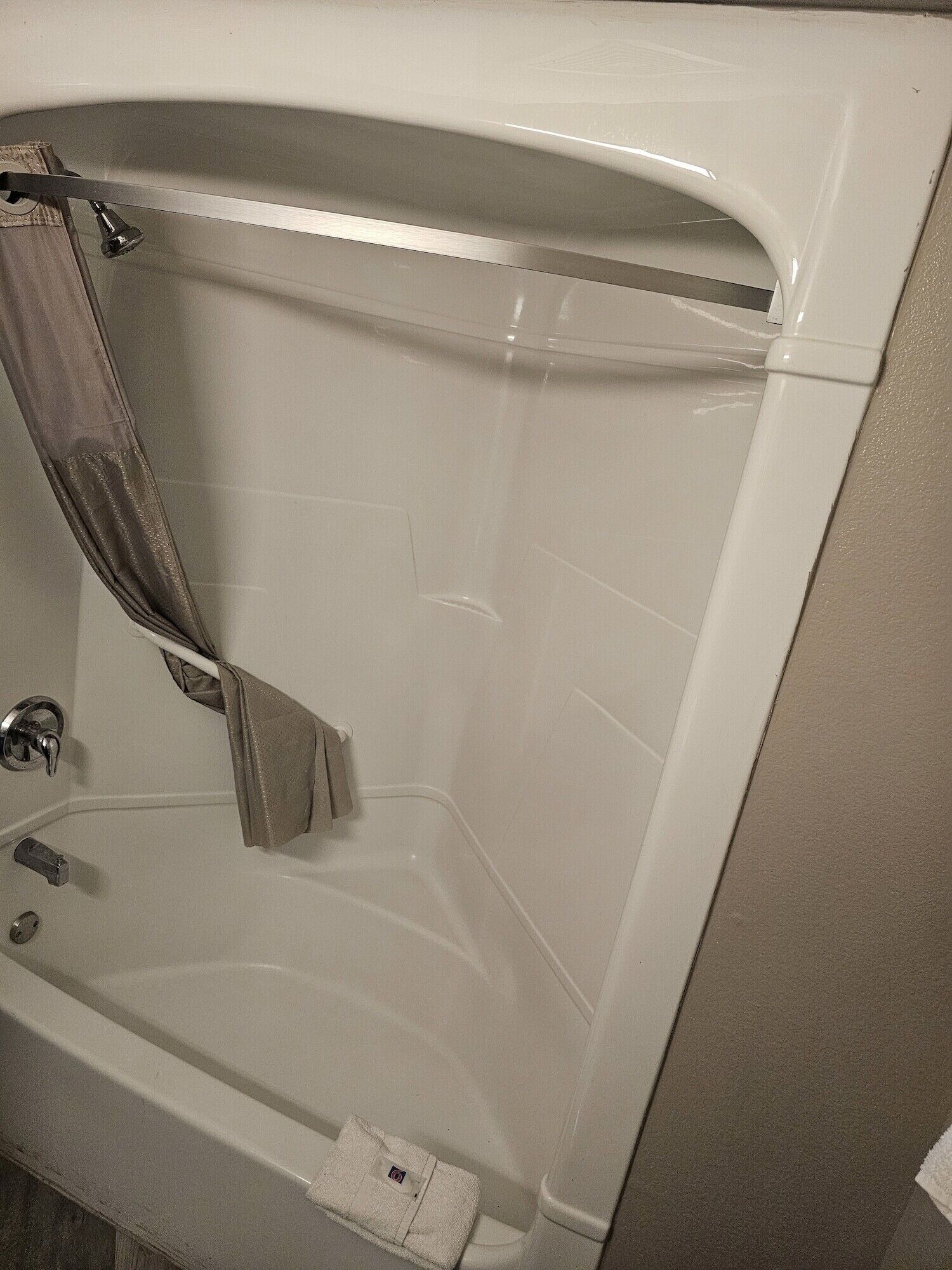 Une baignoire avec un rideau de douche, une douchette et un robinet de réglage.