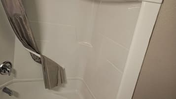 Une baignoire avec un rideau de douche, une douchette et un robinet de réglage.