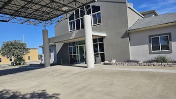 A modern building with a covered entrance, large windows, and a clear sky.