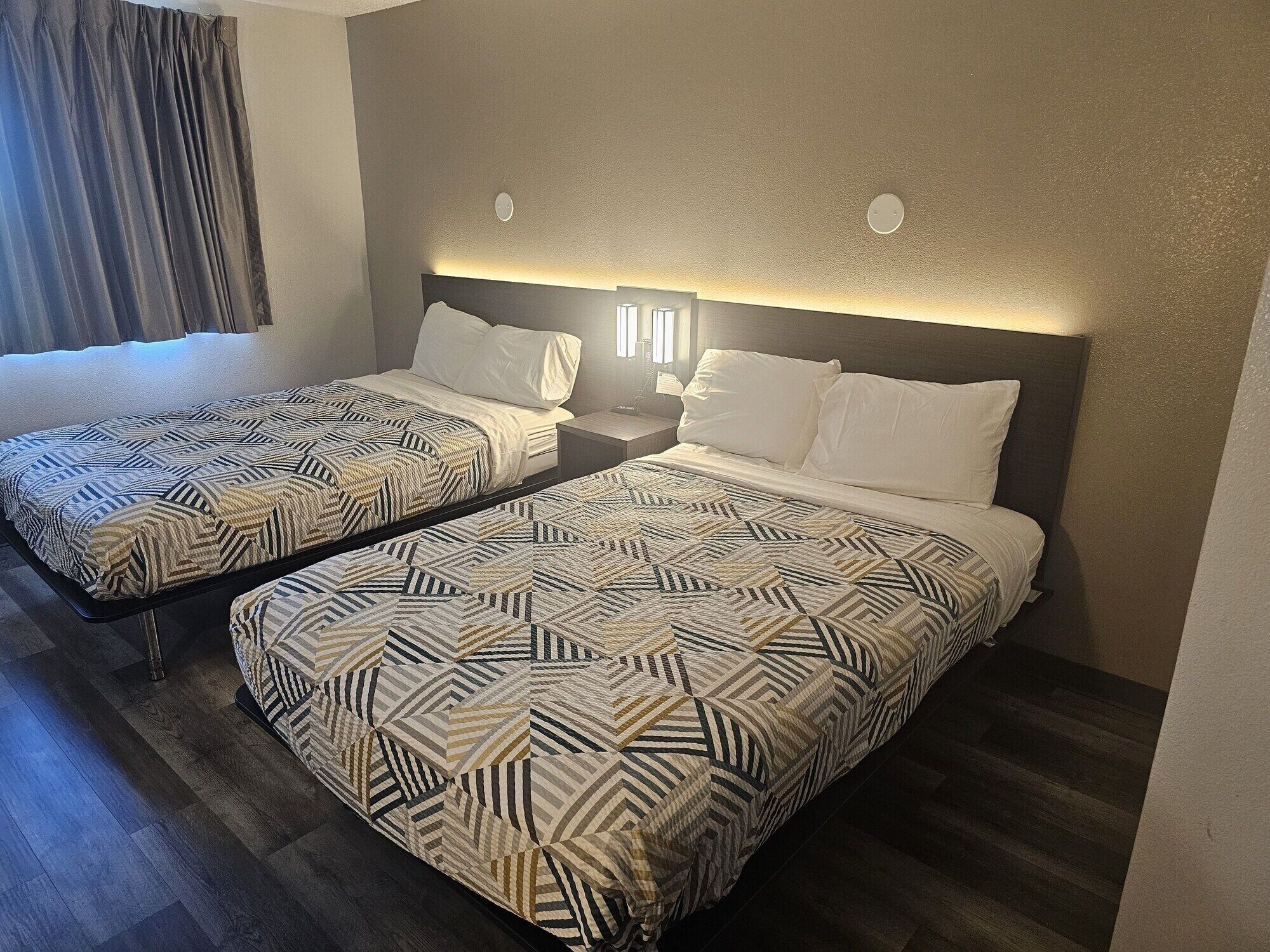 Une chambre d’hôtel avec deux lits, chacun agrémenté de draps à motifs et de lampes de chevet.