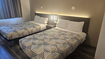 Une chambre d’hôtel avec deux lits, chacun agrémenté de draps à motifs et de lampes de chevet.