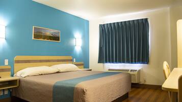 A hotel room with a bed, bedside tables, a desk, and a window with curtains.