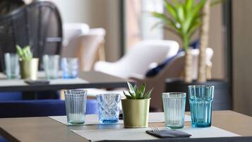 A dining table with a potted plant, a fork, and several glasses.