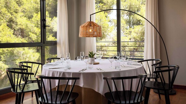 A round dining table set for six with a white tablecloth, black chairs, and a hanging light fixture. - Dolce by Wyndham Barcelona Resort (Sant Esteve Sesrovires)