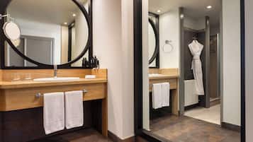 Un baño moderno con tocador de madera, un espejo grande y una zona de ducha con mampara de vidrio.