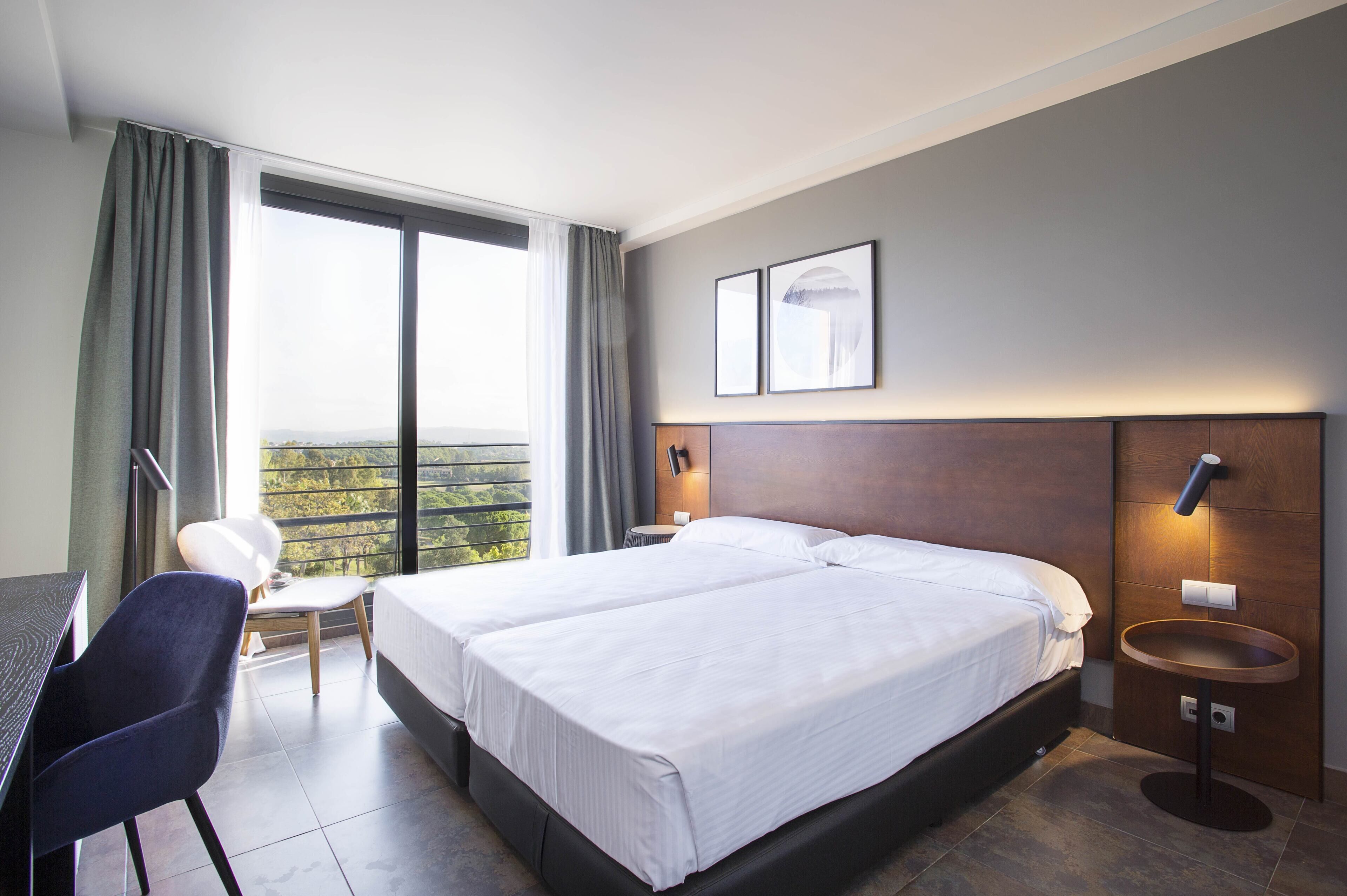 Habitación de hotel con una cama grande, un escritorio, una silla y vistas al exterior.