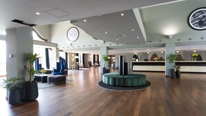 A spacious lobby with a reception desk, seating areas, and potted plants. - Dolce by Wyndham Barcelona Resort (Sant Esteve Sesrovires)