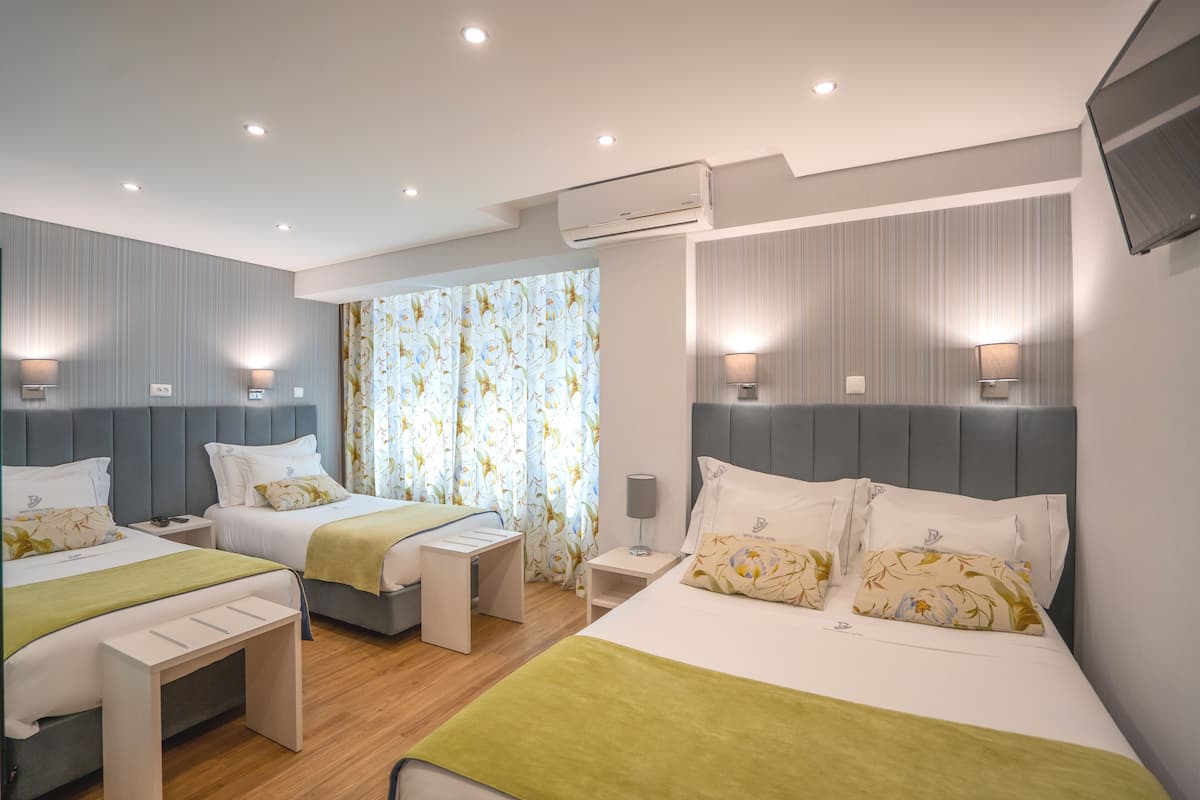 Ein Hotelzimmer mit zwei Betten, einem Schreibtisch und einem Fernseher.