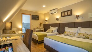 Hotelkamer met twee bedden, een bureau, een stoel, een raam, een airconditioning en een aan de muur hangend kunstwerk.